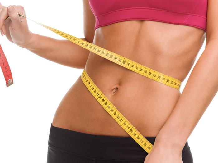 Une femme qui mesure son tour de taille après avoir utilisé une ceinture amincissante
