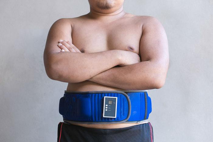 Un homme qui utilise une ceinture vibrante pour perdre son ventre de papa