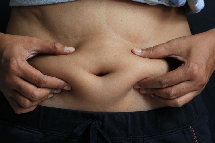 Quand une femme pince le gras de son ventre avec ses mains